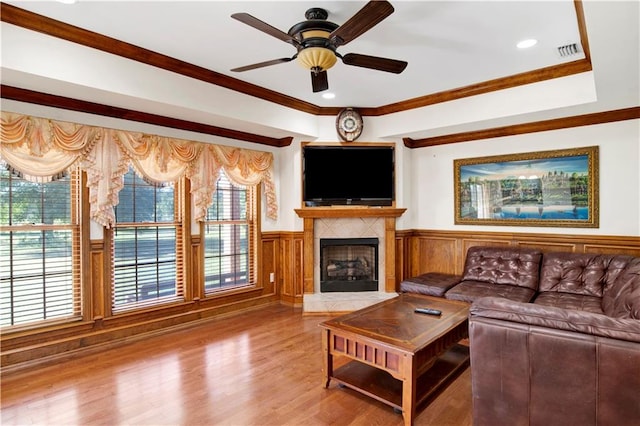 living room with ceiling fan, crown molding, a fireplace, and hardwood / wood-style floors