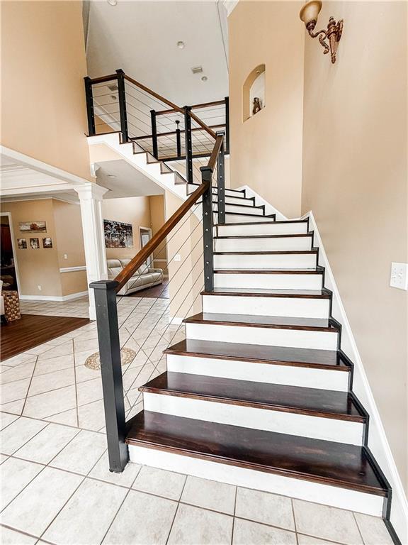 2801 Dog River Rd, Theodore, AL 36582 - stairs featuring a high ceiling, tile patterned flooring, decorative columns, and baseboards