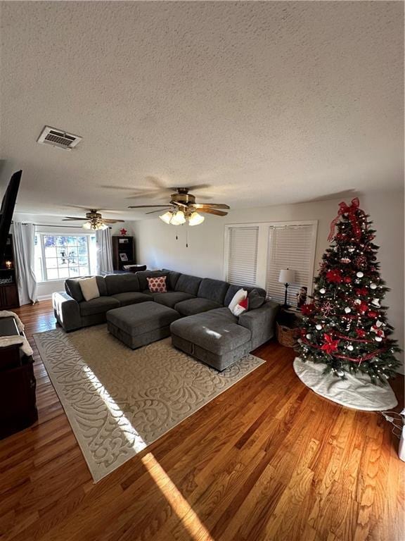 living room with ceiling fan, hardwood / wood-style floors, and a textured ceiling