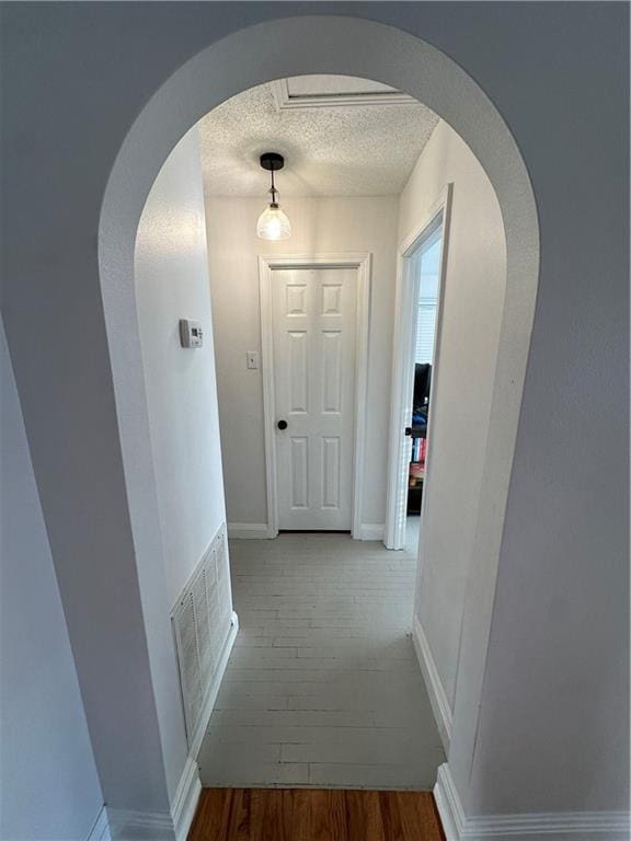 corridor featuring hardwood / wood-style flooring and a textured ceiling