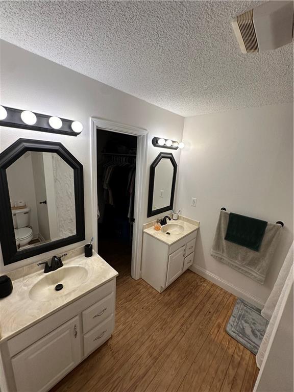 bathroom featuring vanity, hardwood / wood-style floors, a textured ceiling, and toilet