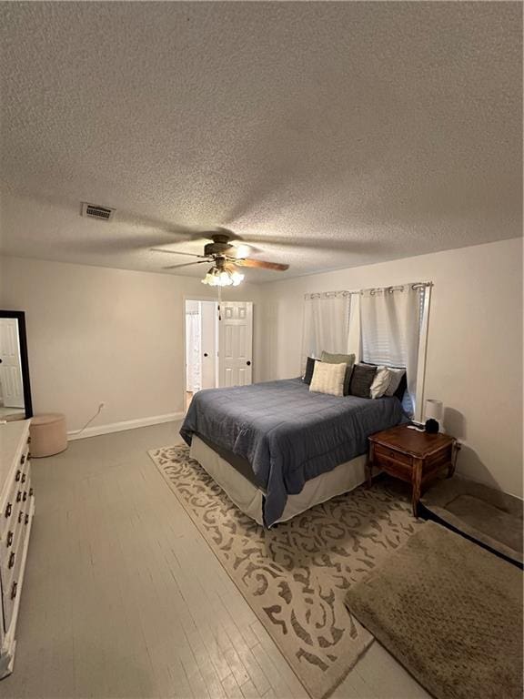 bedroom with a textured ceiling, hardwood / wood-style flooring, and ceiling fan