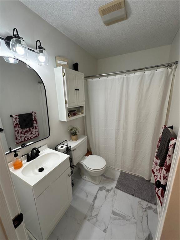 bathroom featuring vanity, toilet, and a textured ceiling