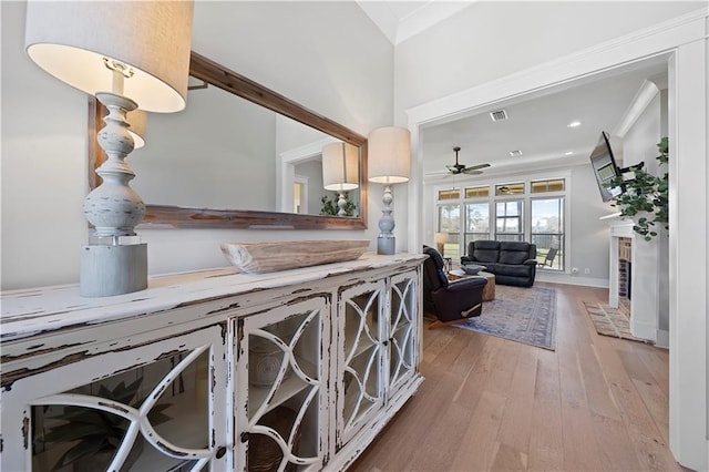 interior space with ornamental molding, hardwood / wood-style flooring, a fireplace, and visible vents