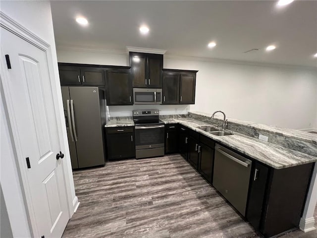 kitchen with kitchen peninsula, light stone countertops, stainless steel appliances, sink, and hardwood / wood-style flooring