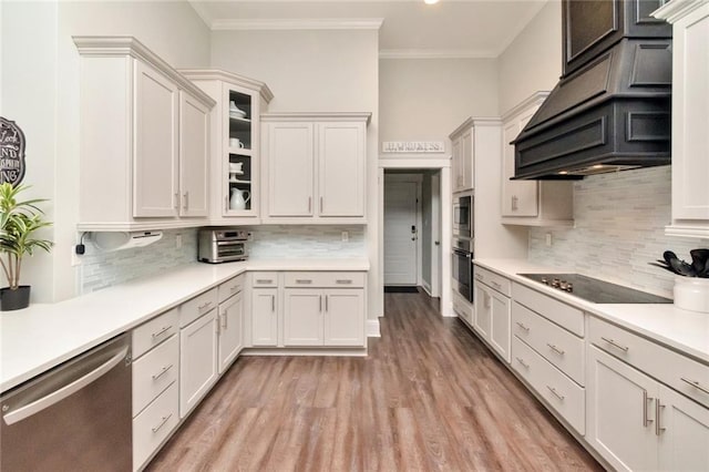 kitchen with stainless steel appliances, white cabinetry, ornamental molding, light hardwood / wood-style flooring, and decorative backsplash