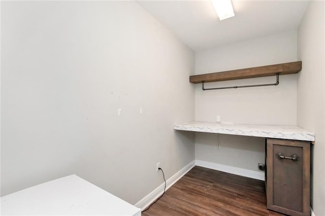 unfurnished office with dark wood-type flooring and built in desk