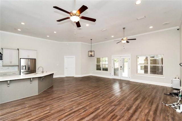 unfurnished living room featuring a towering ceiling, dark hardwood / wood-style flooring, and ornamental molding