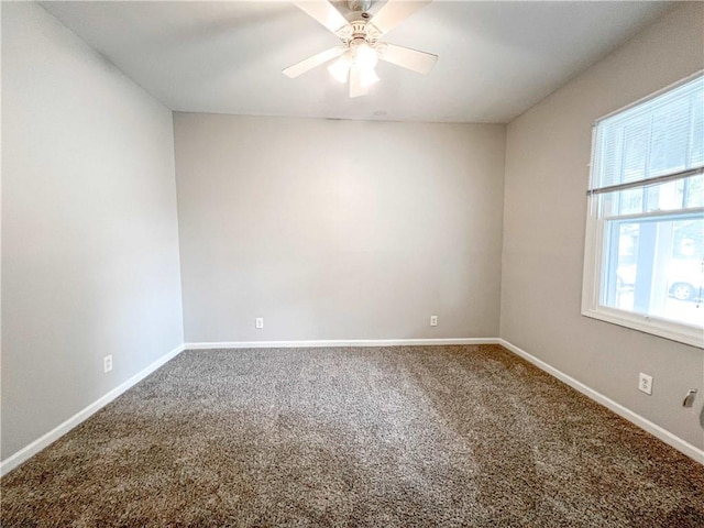 carpeted spare room featuring baseboards and a ceiling fan