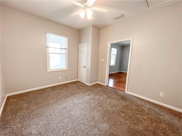 carpeted spare room featuring a ceiling fan, visible vents, and baseboards