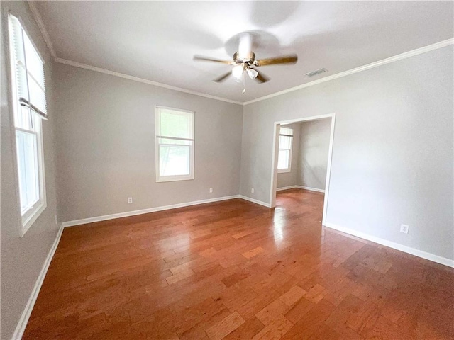 spare room featuring baseboards, ornamental molding, and wood finished floors