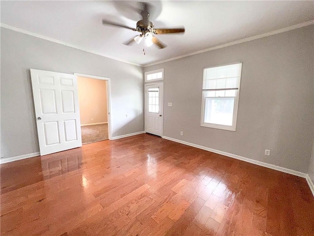 empty room with a ceiling fan, baseboards, ornamental molding, and wood finished floors