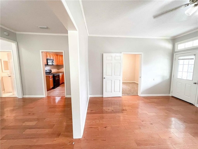 empty room with baseboards, crown molding, and light wood finished floors