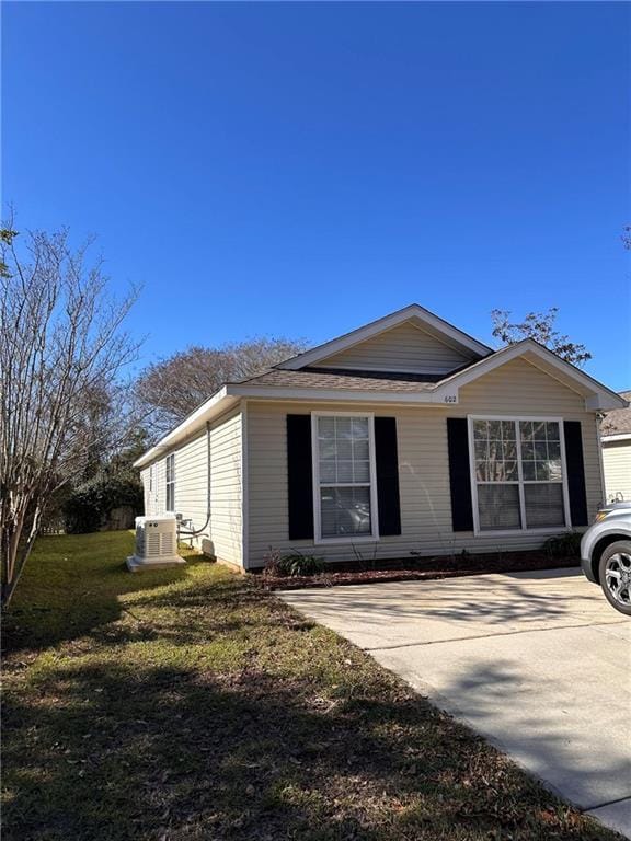 single story home with ac unit and a front lawn