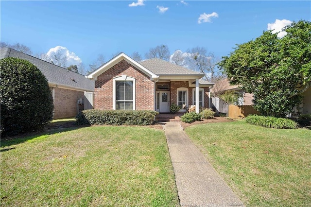 view of front of house with brick siding, a front yard, fence, and a shingled roof