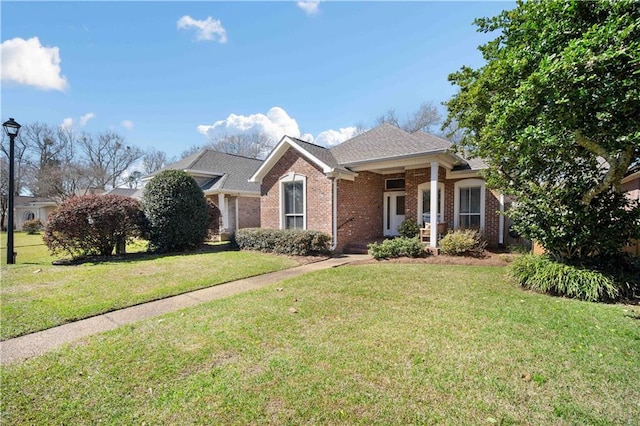 ranch-style home featuring roof with shingles, brick siding, and a front lawn