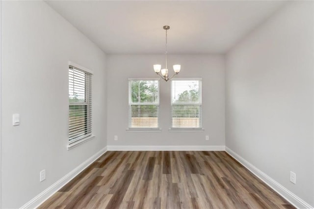 unfurnished dining area featuring dark hardwood / wood-style floors and an inviting chandelier