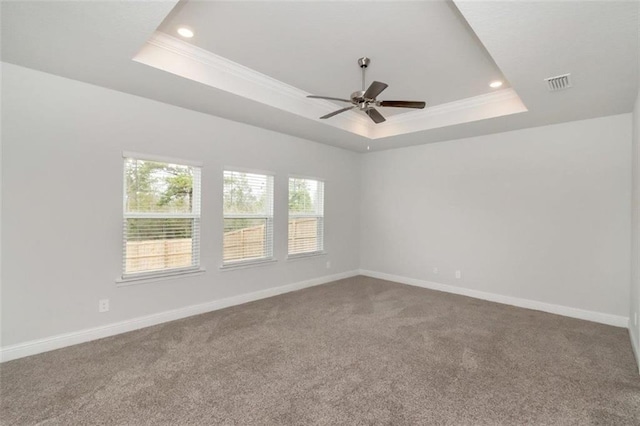 unfurnished room featuring a tray ceiling, crown molding, and carpet