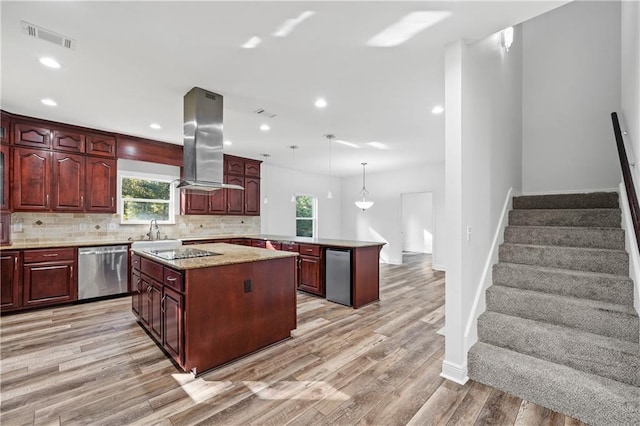 kitchen with island exhaust hood, appliances with stainless steel finishes, hanging light fixtures, light hardwood / wood-style floors, and a center island