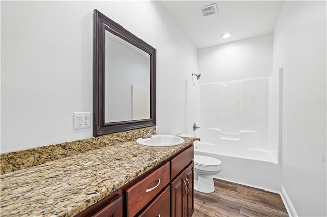 full bathroom with toilet, washtub / shower combination, vanity, and hardwood / wood-style floors