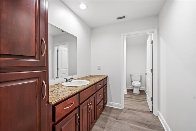 bathroom featuring vanity, hardwood / wood-style flooring, and toilet