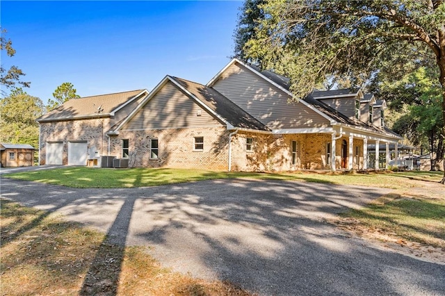 view of front facade with cooling unit, covered porch, and a front lawn