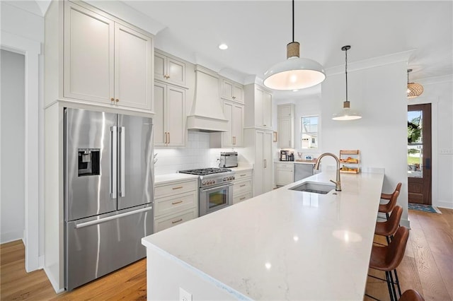 313 Cuban Lilly Dr, Fairhope, AL 36532 - kitchen with premium appliances, custom exhaust hood, a sink, light wood-style floors, and a breakfast bar area