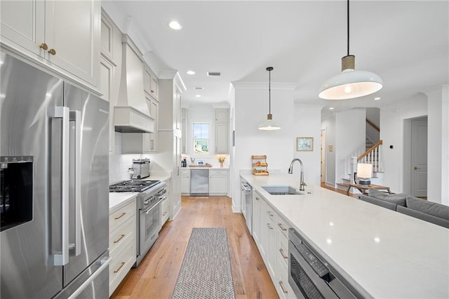 313 Cuban Lilly Dr, Fairhope, AL 36532 - kitchen with appliances with stainless steel finishes, a sink, light countertops, light wood finished floors, and decorative light fixtures