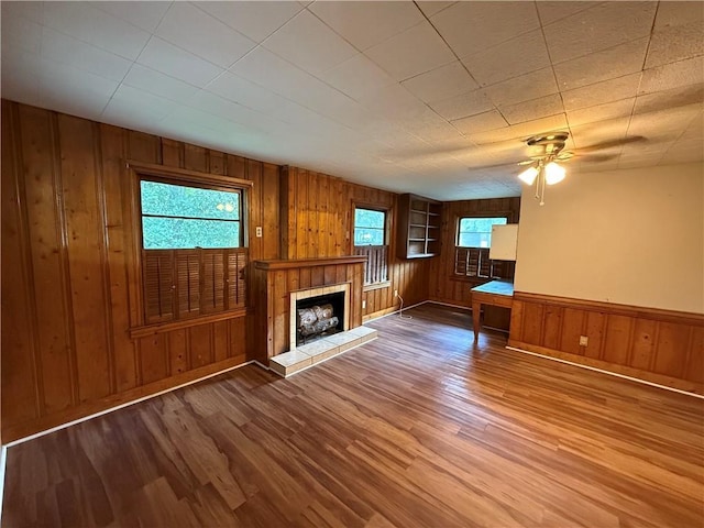 6 Elizabeth Ave, Chickasaw, AL 36611 - unfurnished living room with wooden walls, wood finished floors, a tiled fireplace, and ceiling fan