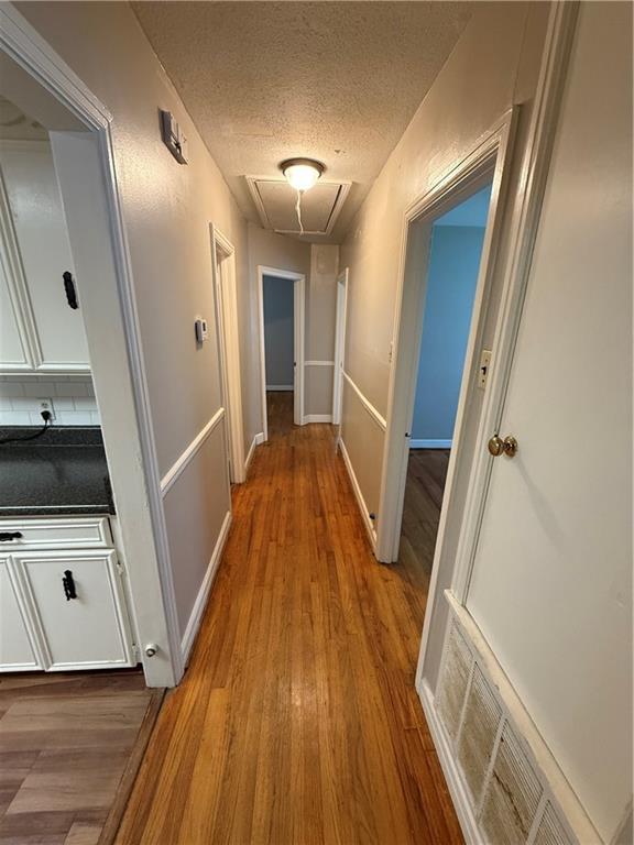 6 Elizabeth Ave, Chickasaw, AL 36611 - hallway featuring attic access, wood finished floors, and a textured ceiling
