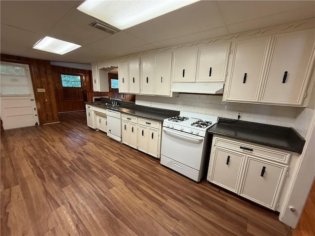 6 Elizabeth Ave, Chickasaw, AL 36611 - kitchen with white appliances, under cabinet range hood, dark countertops, backsplash, and dark wood-style floors