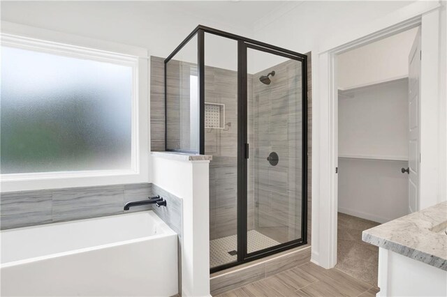 full bathroom with a walk in closet, a garden tub, and a stall shower