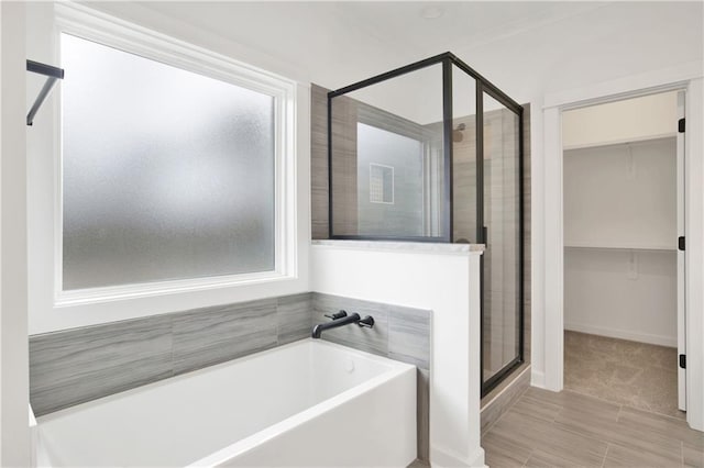 bathroom featuring a bath, a shower stall, and a walk in closet