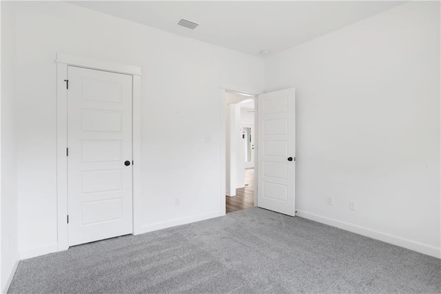 unfurnished bedroom with visible vents, carpet floors, and baseboards