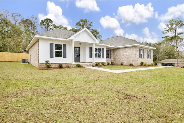 view of front of property featuring brick siding, central air condition unit, a front lawn, and fence