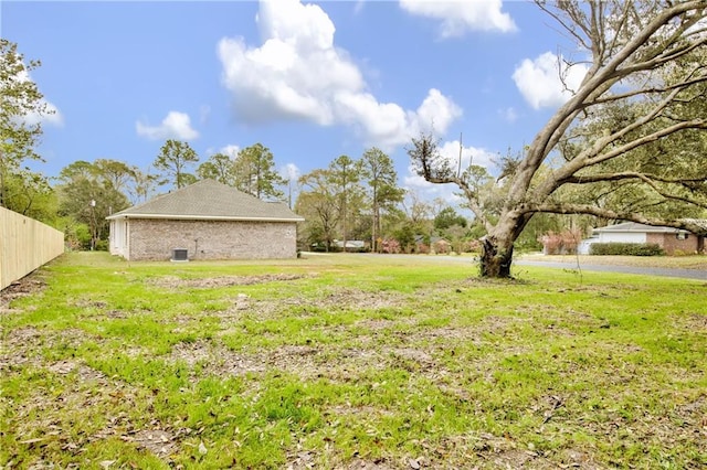 view of yard featuring fence and central AC