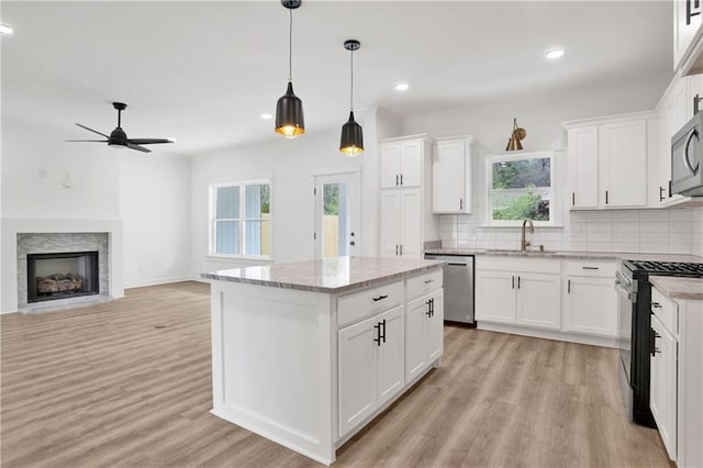 kitchen with backsplash, appliances with stainless steel finishes, light wood-style floors, a ceiling fan, and a sink