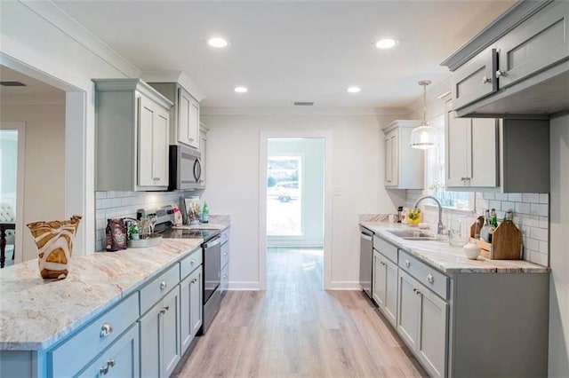 kitchen with tasteful backsplash, hanging light fixtures, light hardwood / wood-style flooring, crown molding, and stainless steel appliances