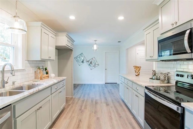 kitchen with pendant lighting, sink, stainless steel appliances, and backsplash