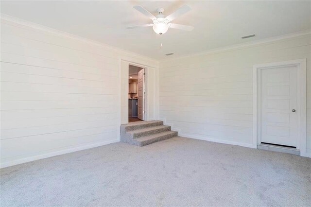 2305 Cedar Ky, Mobile, AL 36695 - carpeted empty room with visible vents, ornamental molding, stairs, wood walls, and ceiling fan