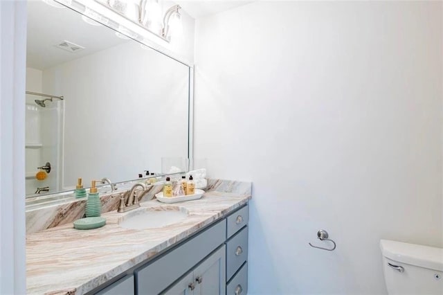 bathroom with vanity, a shower, and toilet