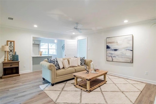 living room with ornamental molding, light wood-type flooring, and ceiling fan