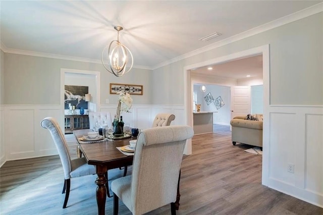 dining room with ornamental molding, a notable chandelier, and hardwood / wood-style floors