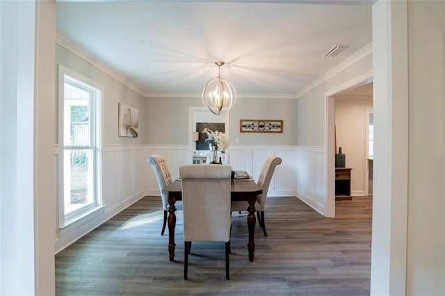 dining space with dark wood-type flooring, crown molding, and a notable chandelier