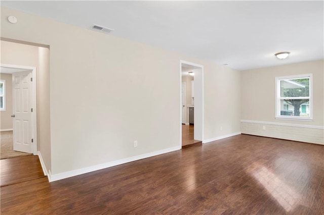 unfurnished room with dark wood finished floors, visible vents, and baseboards