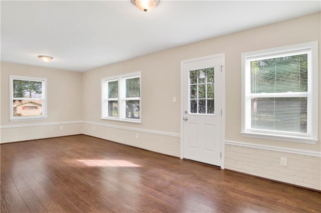 interior space with brick wall, dark wood finished floors, and a wealth of natural light