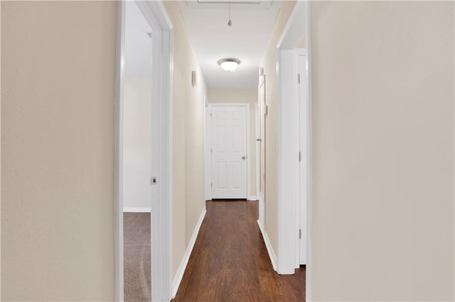 corridor featuring dark wood-style flooring, attic access, and baseboards