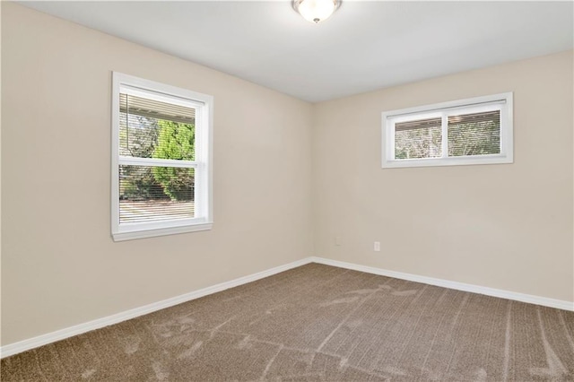 empty room featuring carpet and baseboards