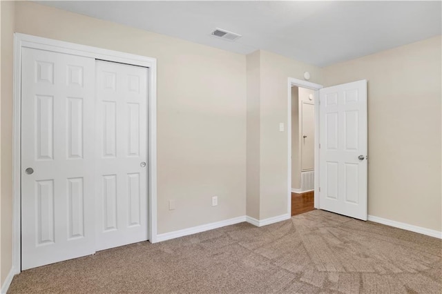 unfurnished bedroom featuring light carpet, a closet, visible vents, and baseboards