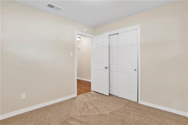 unfurnished bedroom featuring a closet, carpet, visible vents, and baseboards